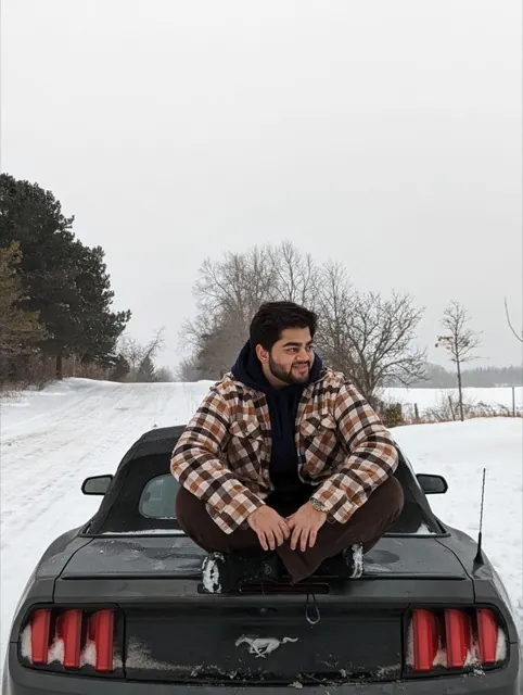 Abbas sitting on his convertible Mustang in the snow